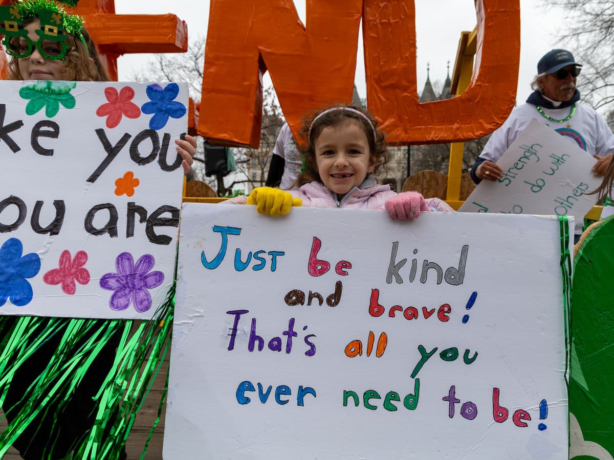 A young marcher holding a hand-lettered sign that reads “Just be kind and brave! That’s all you ever need to be!”