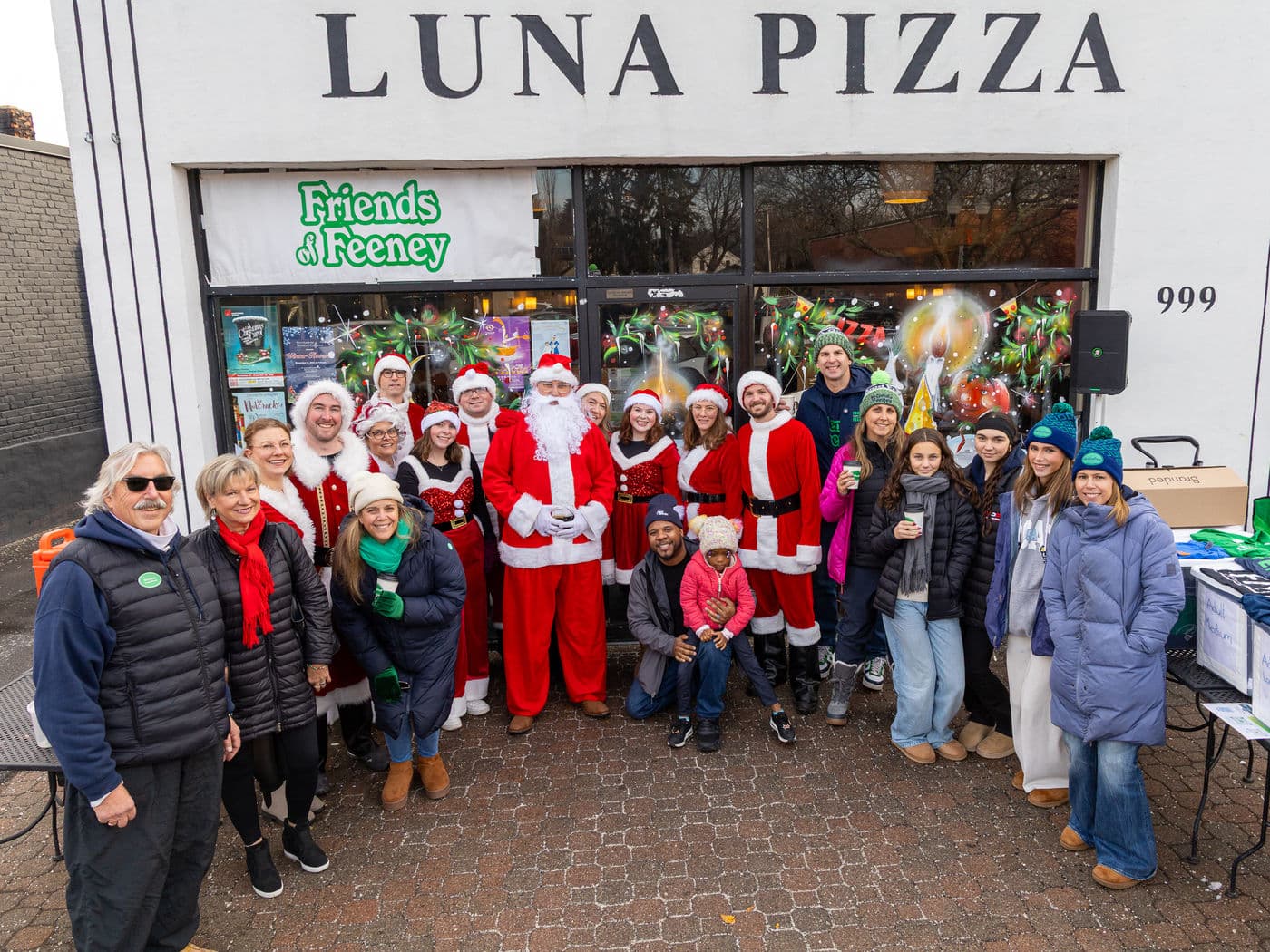 A crowd of toy drive helpers, Santa among them, gathered outside Luna Pizza
