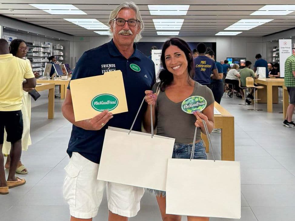 Two people inside a store holding shopping bags and #BeAGoodFriend stickers, one wearing a Friends of Feeney polo