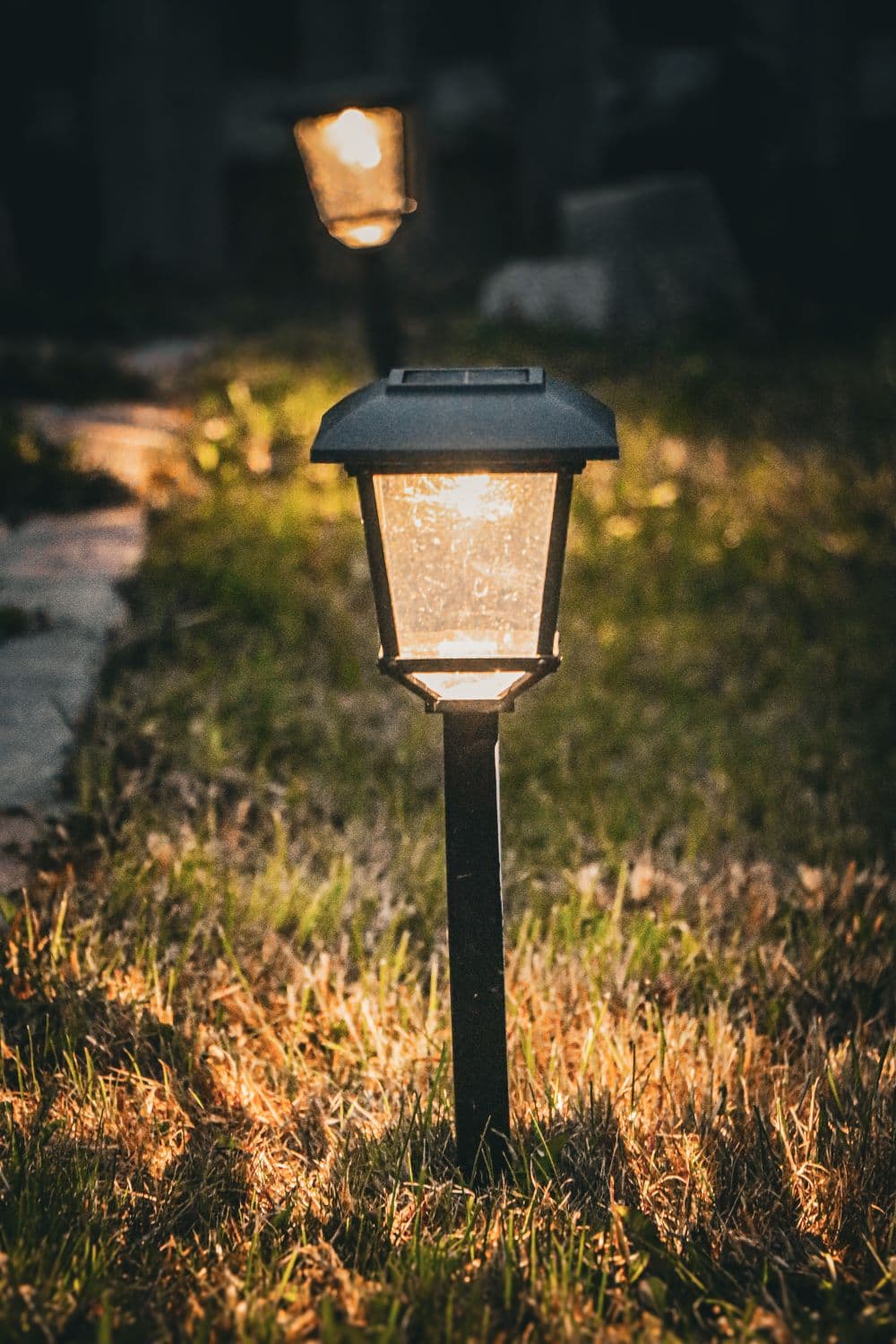 A low path light glowing over a lawn edge at dusk