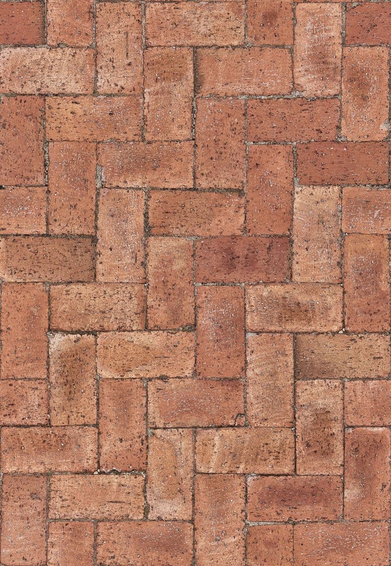Close-up of red clay brick pavers laid in a herringbone pattern