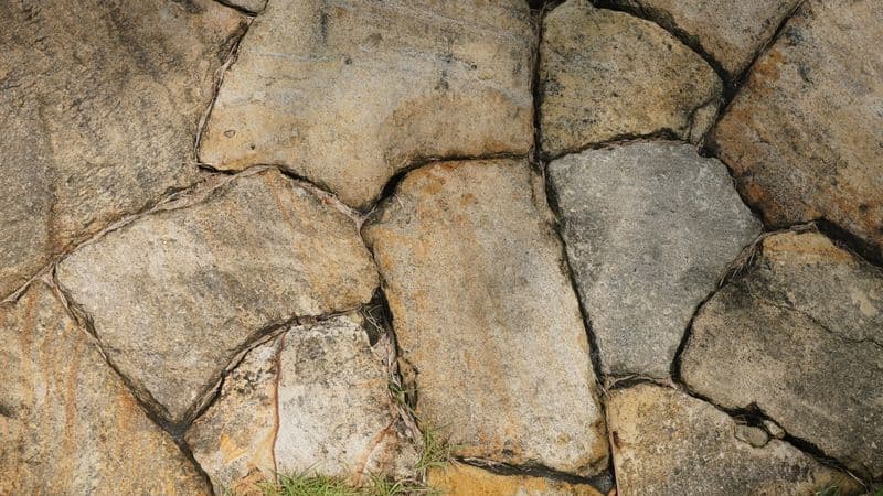 Close-up of rounded tan and gray fieldstones fitted into a wall