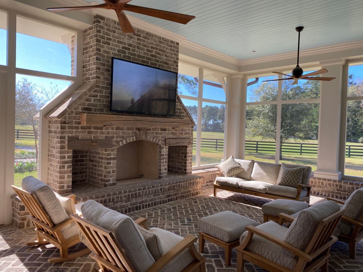 Sunroom with a brick fireplace, rocking chairs and windows on three sides