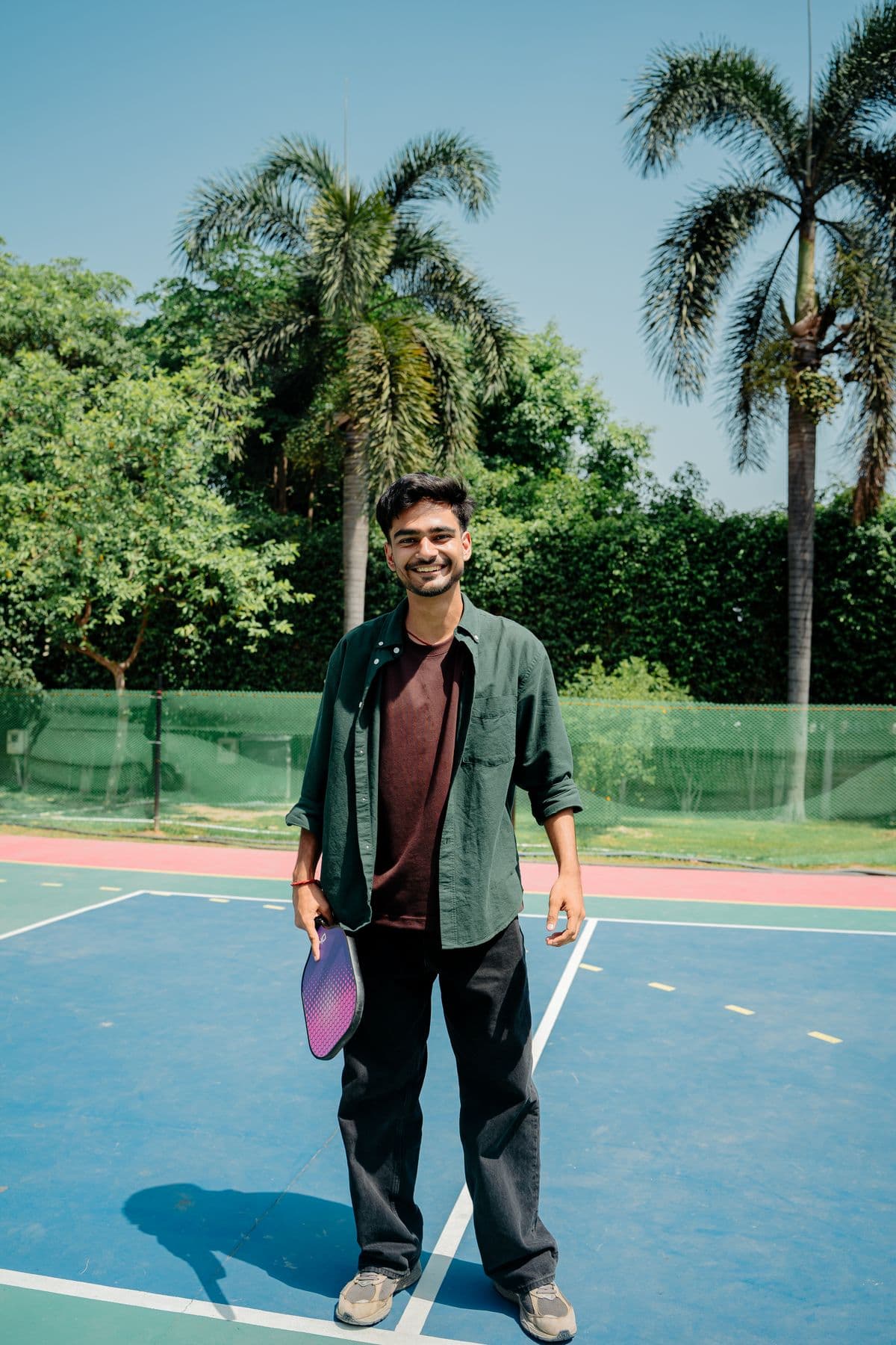 Rohan Mehta smiling on a blue pickleball court with a paddle in his hand
