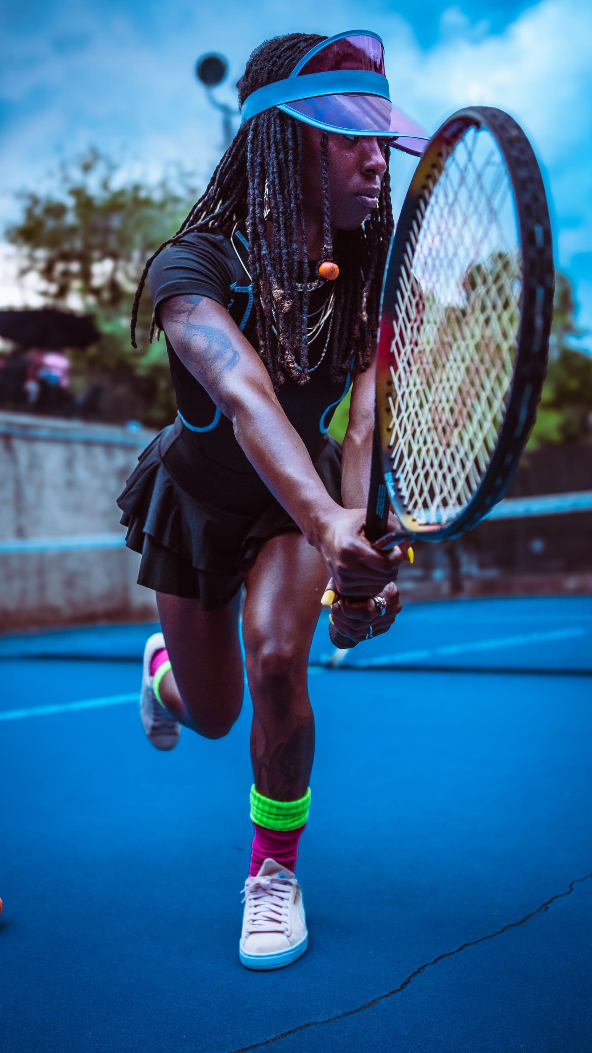 A player in a visor lunges into a two-handed backhand on a blue hard court