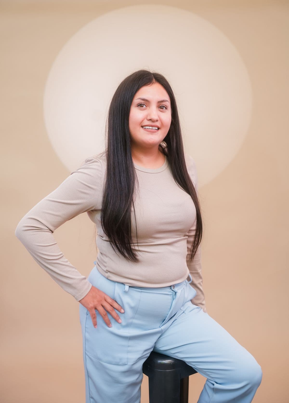 Sofia Ramírez smiling, one hand on her hip, in front of a pale circular backdrop
