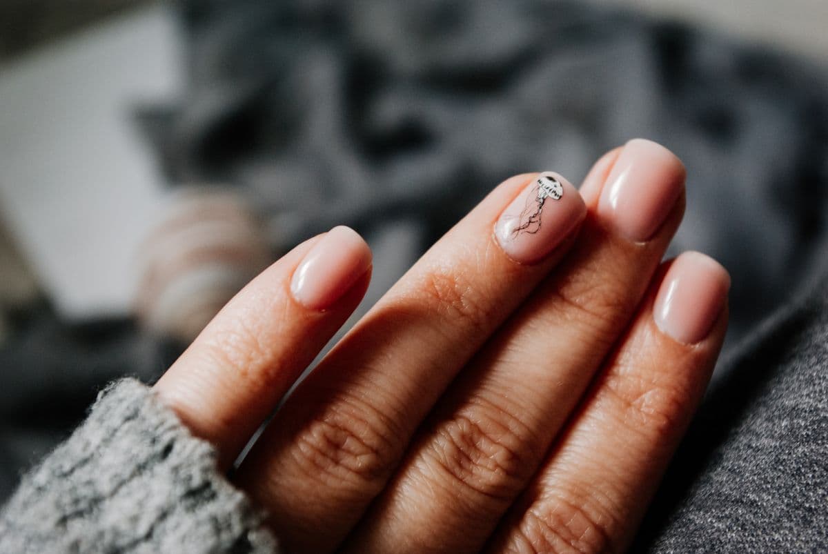 Sheer pink nails with a tiny hand-painted jellyfish on one accent nail