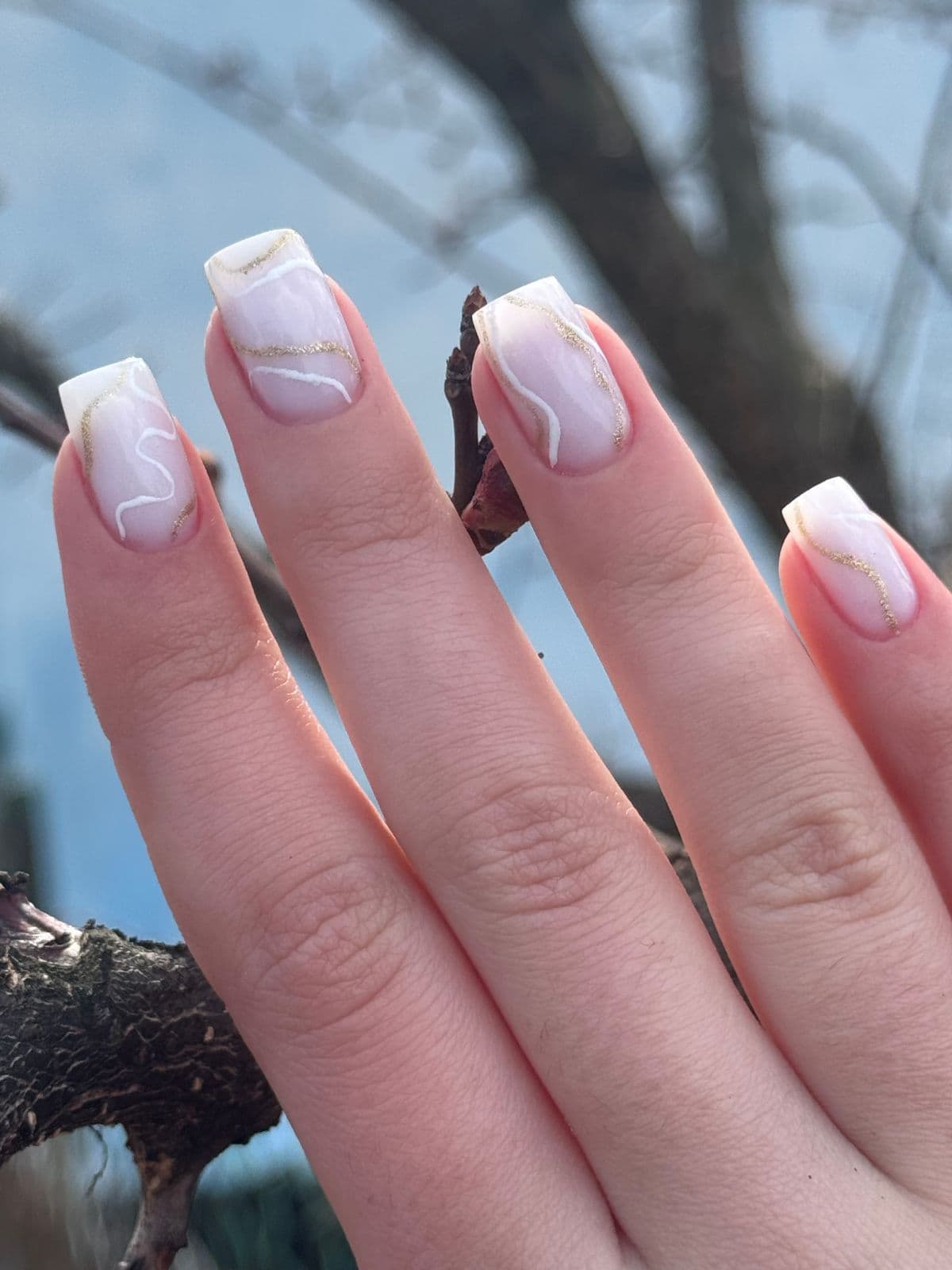 Milky French tips traced with thin white and gold swirling lines