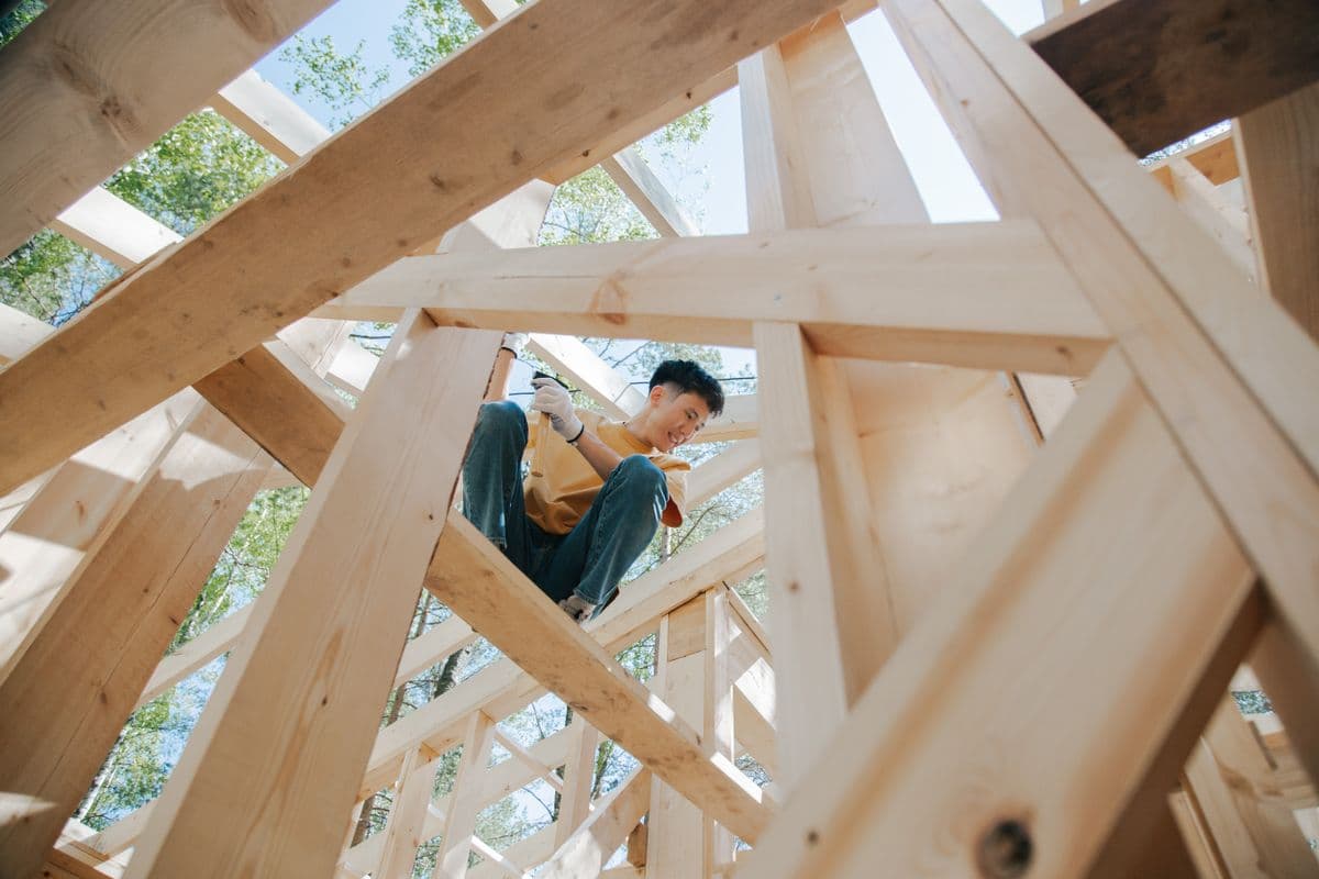 Carpenter climbing through a web of fresh roof trusses