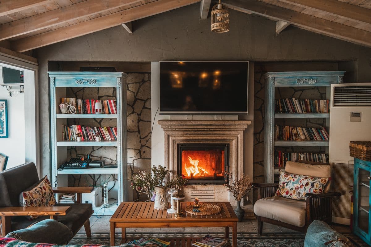 Family room with a stone fireplace, built-in bookcases, exposed beams and comfortable chairs