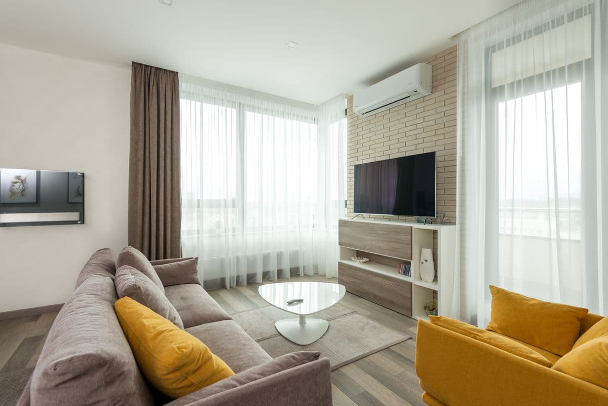 Lounge with a gray sofa, yellow armchair and a wall-mounted TV
