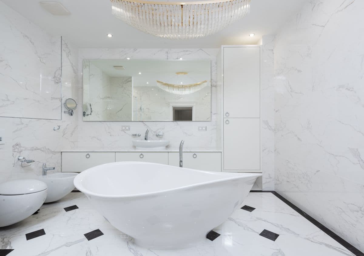White marble bathroom with a sculpted freestanding tub and a long floating vanity