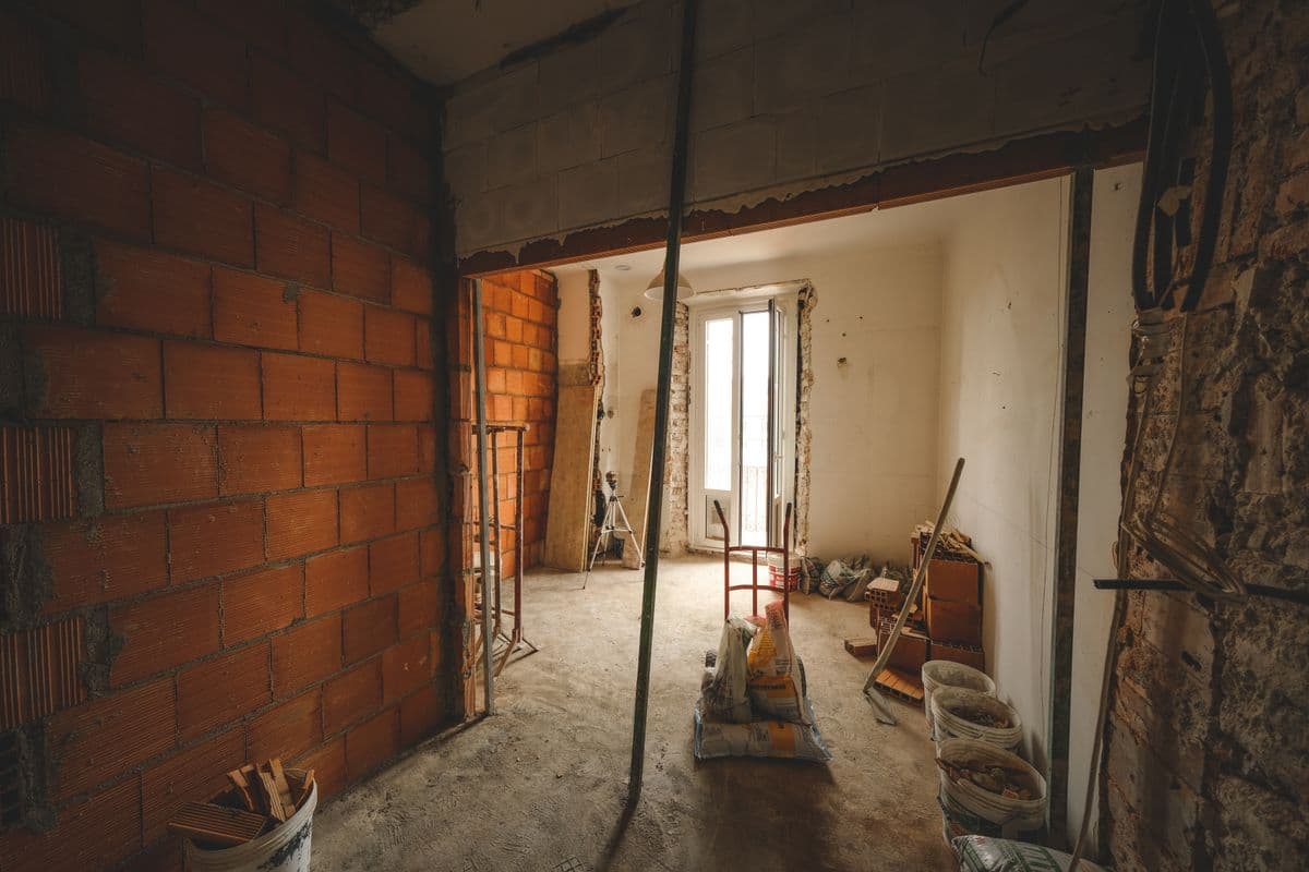 Old house interior opened down to brick and lath, with debris on the subfloor