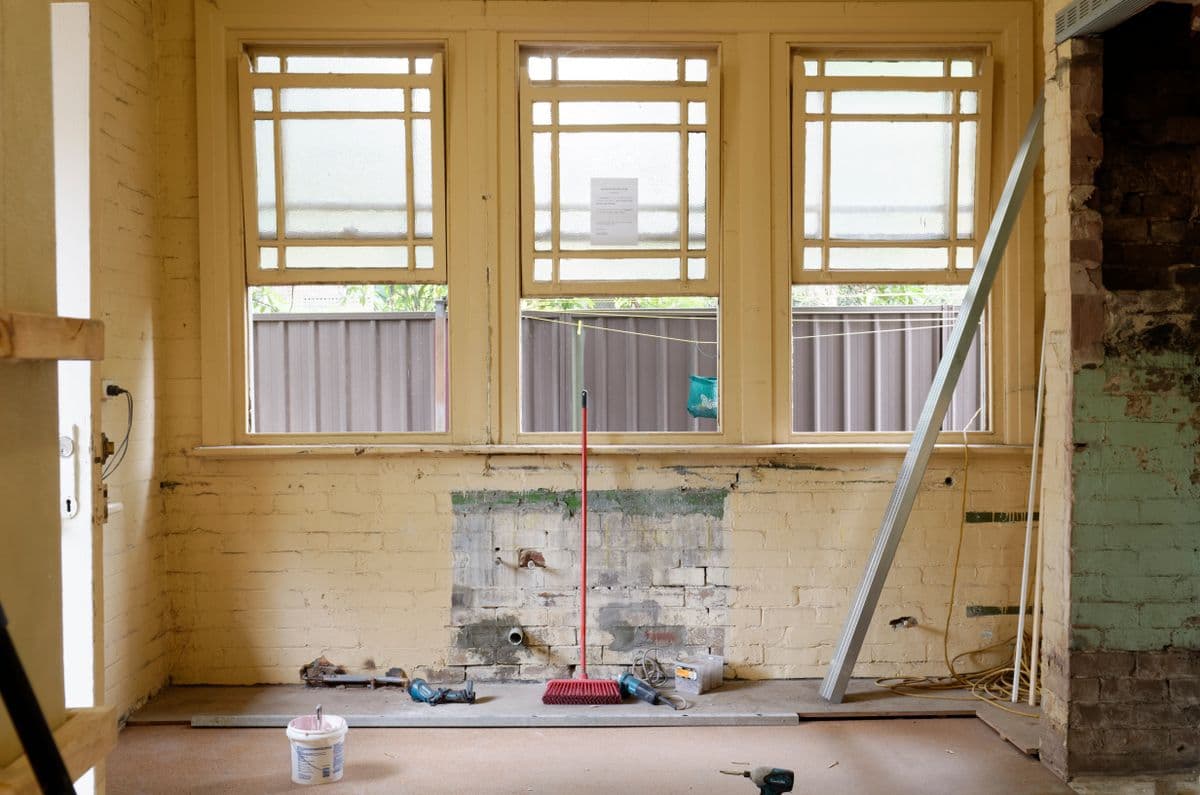 Stripped room with original divided-light windows and patched brick, ready for new walls