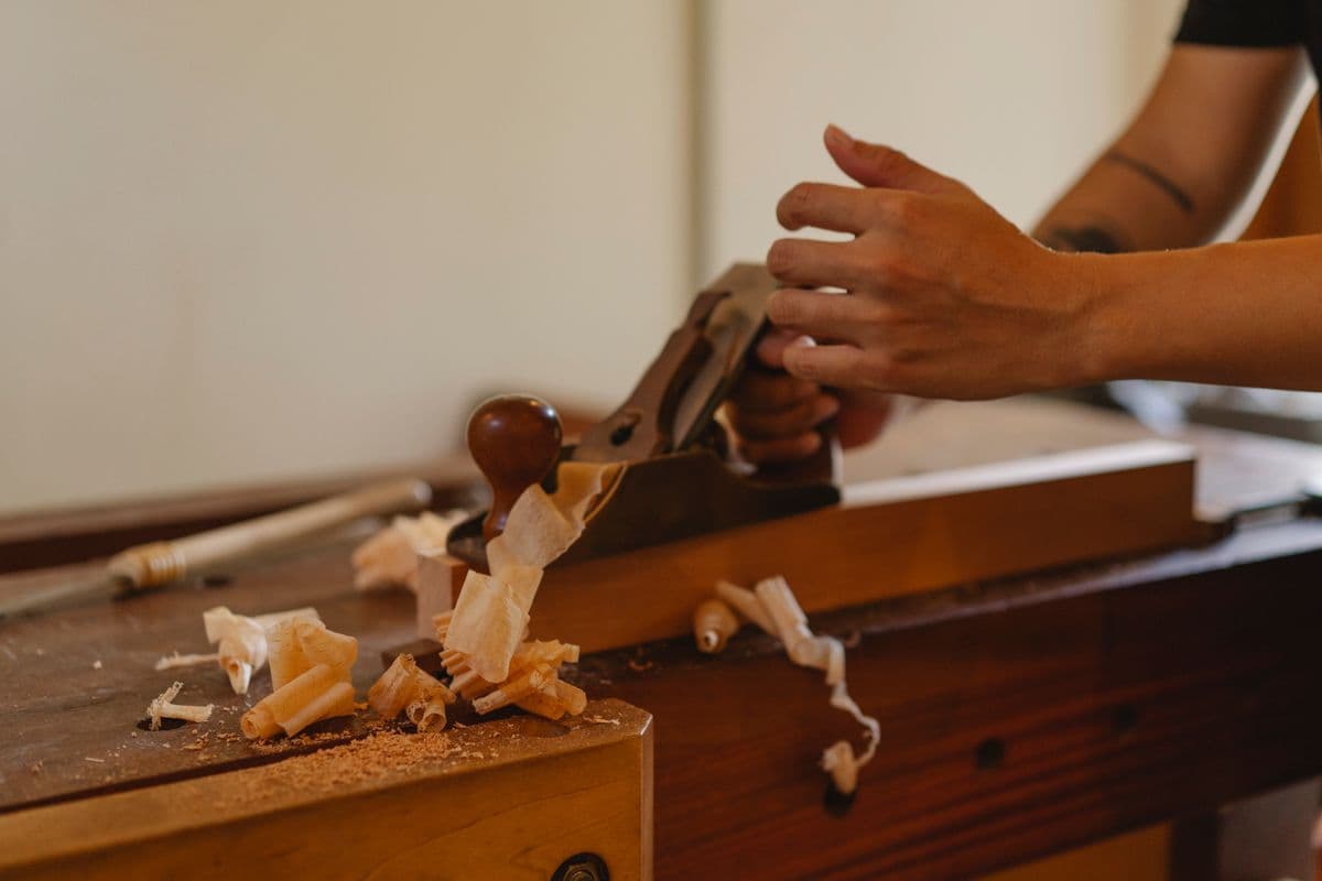 Hand plane curling shavings off a board on a workbench