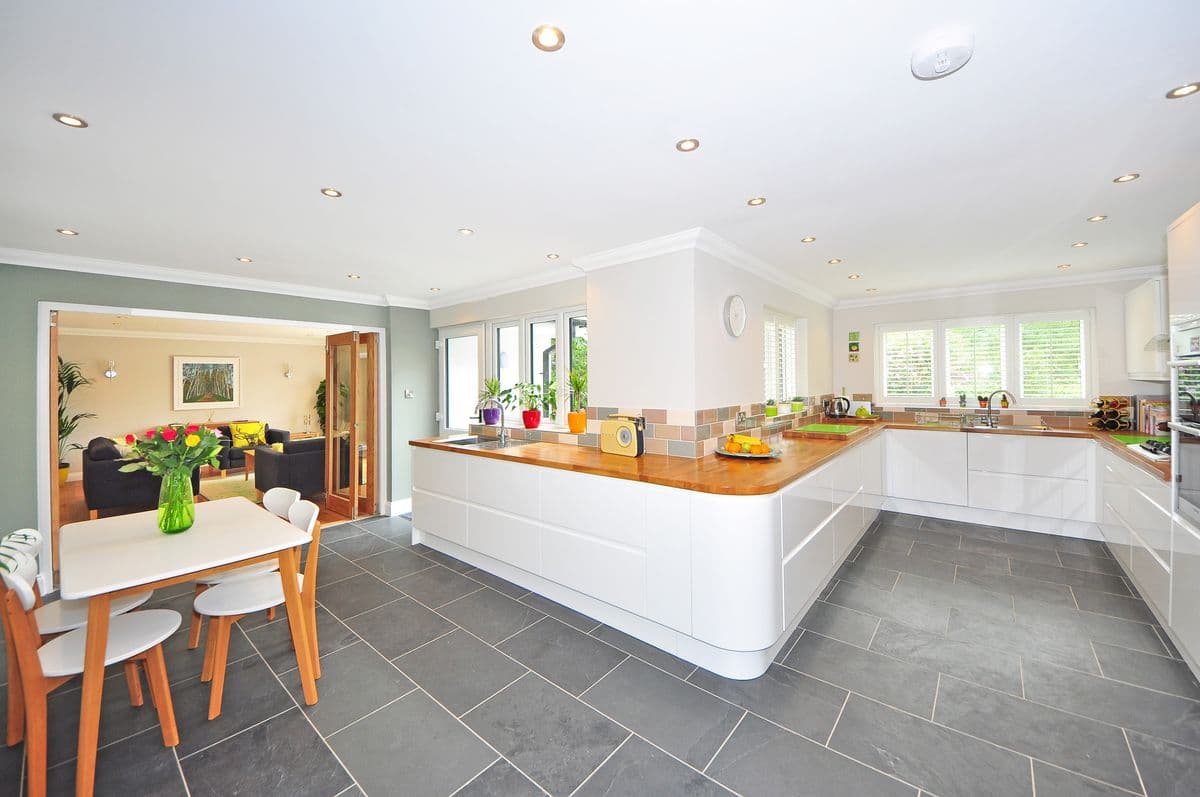 Wraparound white kitchen with a wood countertop, slate floor and a view into the living room