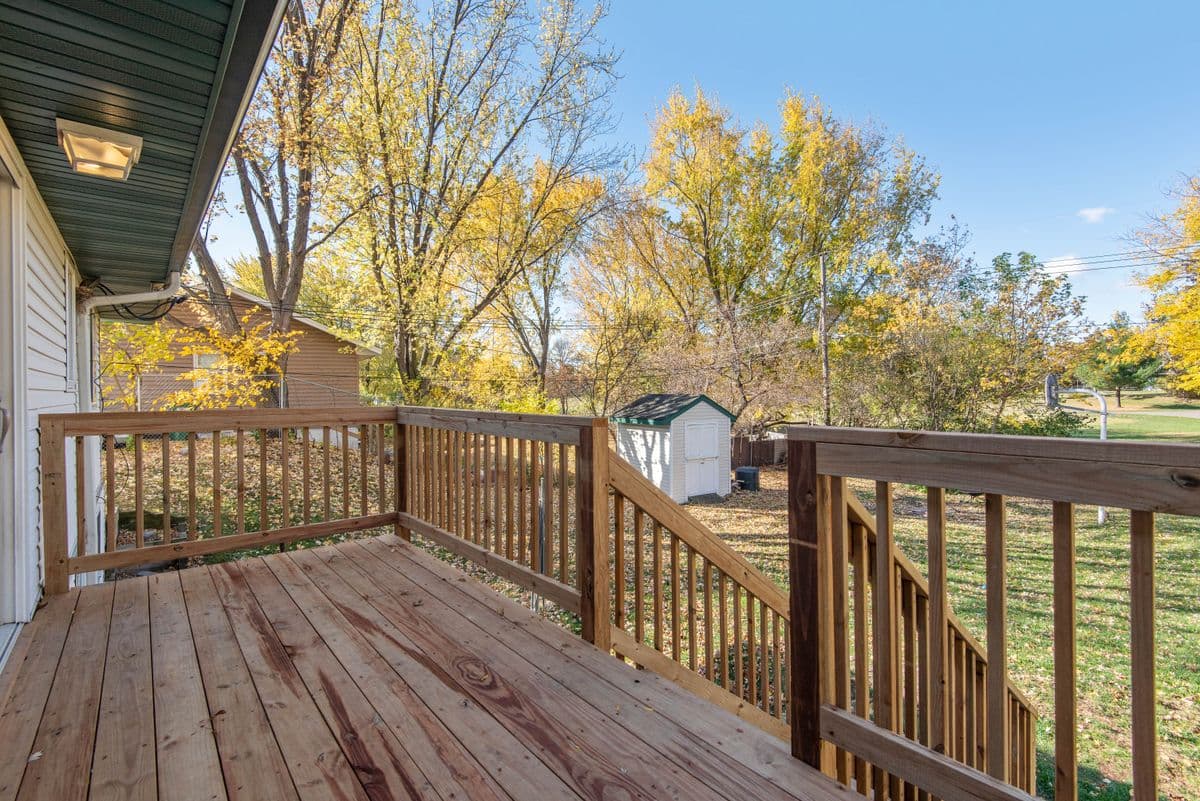 Weathered pressure-treated deck and railing looking out on an autumn backyard