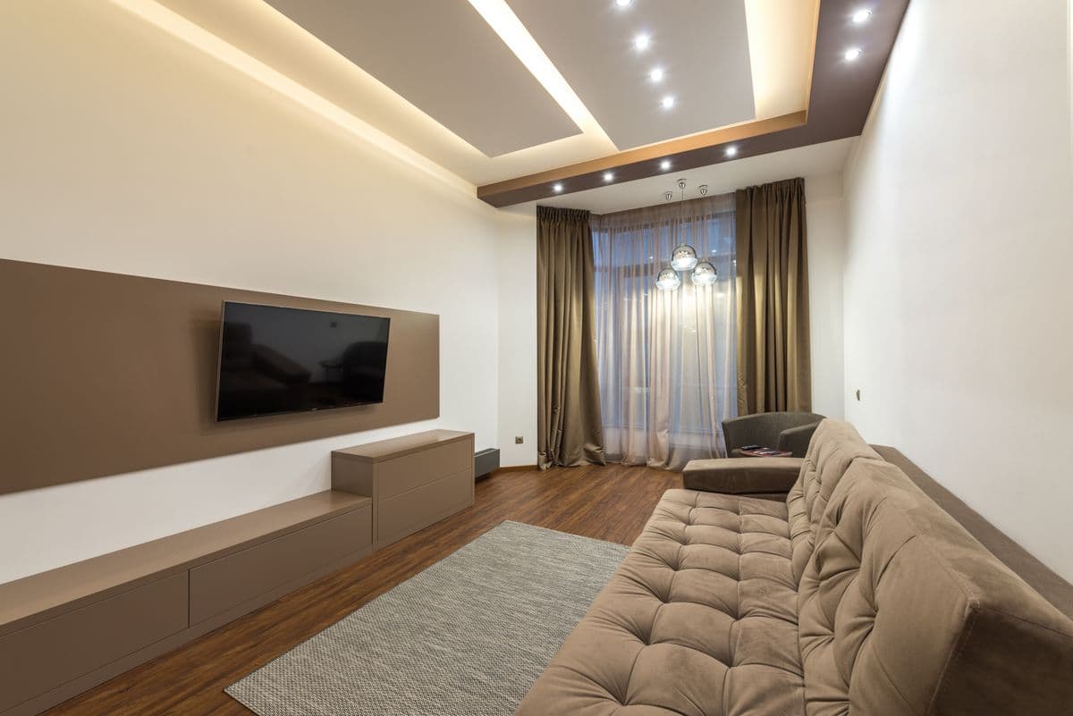Long media room with a built-in TV wall, recessed ceiling lights and a deep sofa