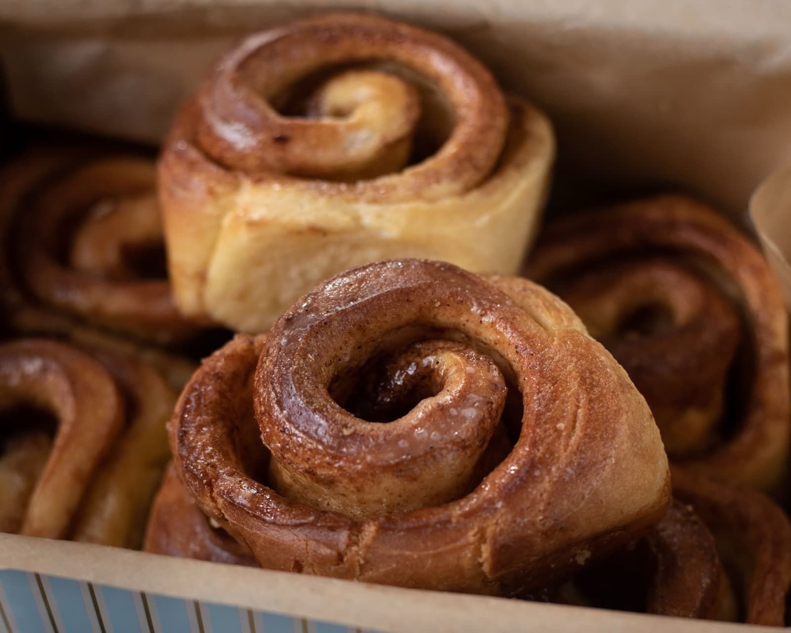 Glossy maple-glazed sticky buns packed close together in a pan